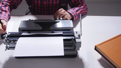 Konzept zum Tag des Schriftstellers. Junger männlicher Schriftsteller in einem dunklen Raum tippt auf einer Schreibmaschine