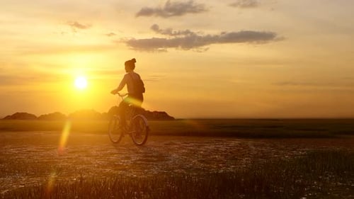 Mädchen wandert mit dem Fahrrad bei Sonnenuntergang