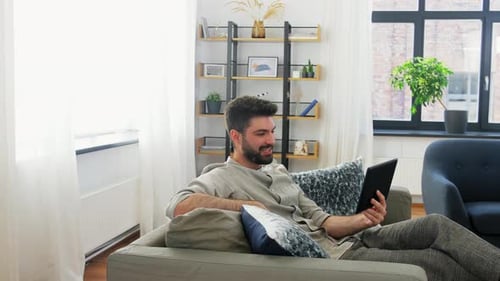 Man Relaxing on Sofa using Tablet for Video Call