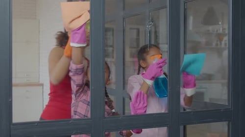 Woman and Children Cleaning Window Together
