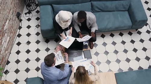 Four Male and Female Business Colleagues which Working with Reports with Charts