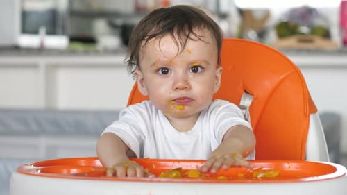 Infant Eating Messy Food in High Chair