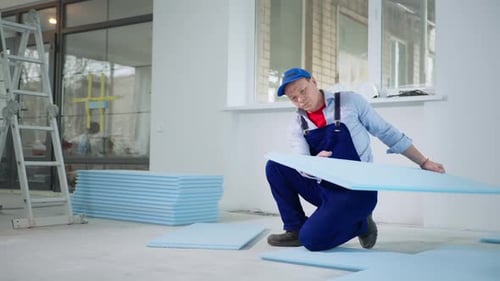 Man Installing Insulation Panels in Bright Room