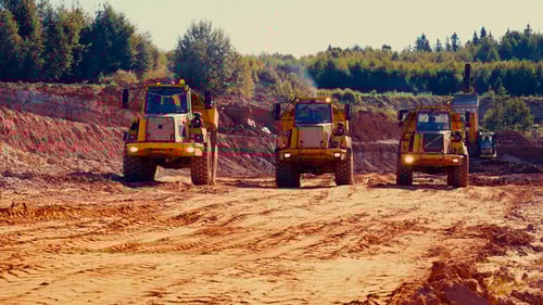 Heavy Yellow Dump Trucks Drive at a Mining Site
