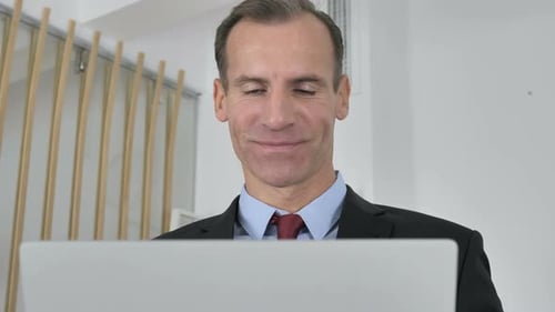 Smiling Businessman Video Conferencing on Laptop Indoors