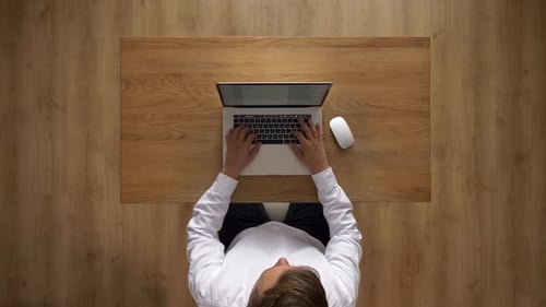 Young Adult Working on Laptop at Wooden Desk