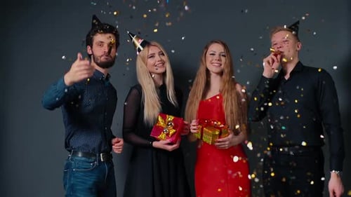 Two Cheerful Guys Blow a Festive Whistle and Throw Up a Colorful Confetti