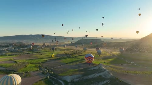 Hot air balloons fly over the mountainous landscape of Cappadocia, Turkey.