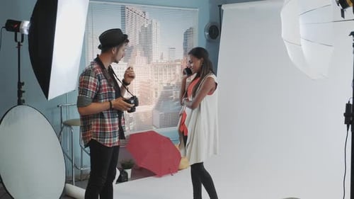 Atraente modelo africana falando em smartphone enquanto o fotógrafo pede para continuar trabalhando