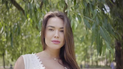 Woman Posing Outdoors Surrounded by Green Trees