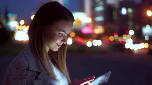 Attractive Girl Looking at the Tablet, Against the Night Road