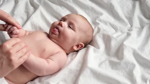 Infant Receiving Gentle Massage on White Sheet