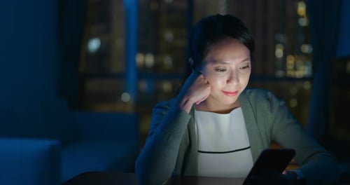 Woman Using Mobile Phone in Dark Room at Night