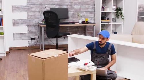 Man Assembling Furniture Using Instructions on Laptop