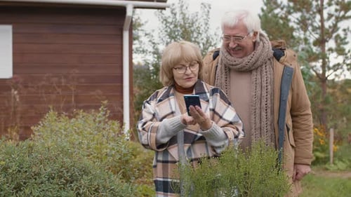 Senior Couple Using Mobile Phone in Garden