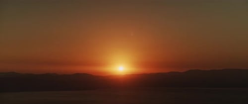 Beautiful landscape with sunset over the big lake and the mountains. Tilting down to up shot.
