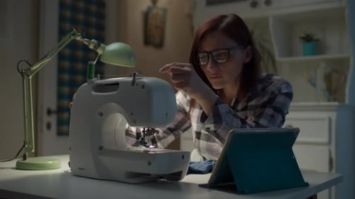 Woman Threads Needle of Sewing Machine at Home