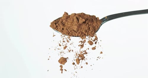 Spoon of Brown Powder Slowly Crumbles