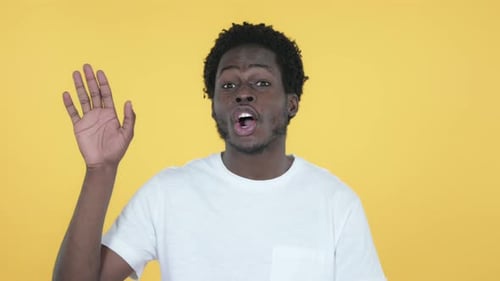 Afrikanischer Mann winkt Hand zur Begrüßung, gelber Hintergrund