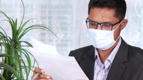 Young Adult Reads Paper with Face Mask