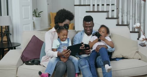 Familia afroamericana en casa mientras revisa videos divertidos en una tableta