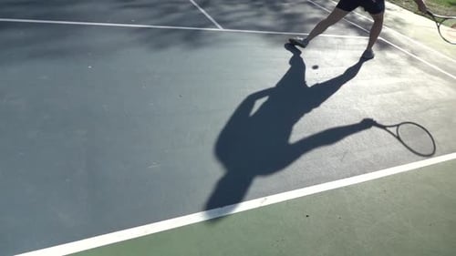 Tennis Player Shadow on Court Hitting Ball