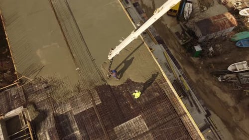 Betonzement auf dem Dach eines im Bau befindlichen Gebäudes mit einer Betonpumpen-LKW-Maschine