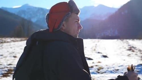 Side View of Young Hiker Going Nordic Walking with Sticks on Snowy Trail in Field at Mountain