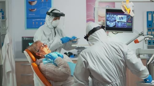 Dentist Examines Patient in Full Protective Gear