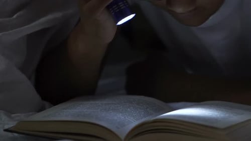 Child Lying Under Covers with Book, Turning on Torch to Read, Books Addiction