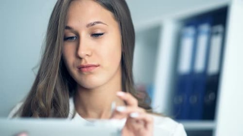 Femme d'affaires attrayante à l'aide d'une tablette numérique au bureau