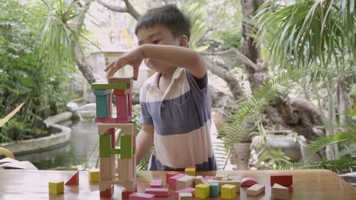 Asiatischer Junge spielt Holzblockspielzeug auf dem Tisch für Kreativität und Entwicklung mit Spaß.