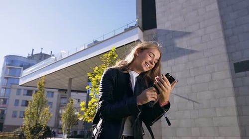Woman Using Smartphone, Laughing in Urban Setting