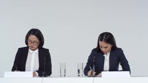 Women Signing Documents at a Conference Table