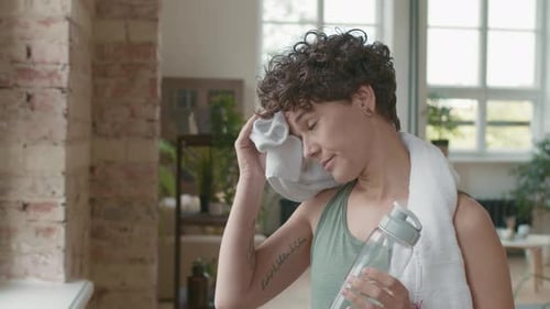 Woman Wipes Face with Towel After Workout