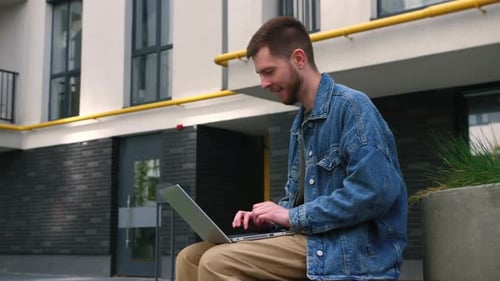Surprised Man Getting Good News on Laptop Outside Business Center