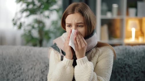 Woman in Scarf Blowing Nose in Napkin