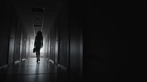 Silhouette of Woman Walking in Dark Hallway