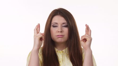 Young Woman Makes a Wish with Fingers Crossed