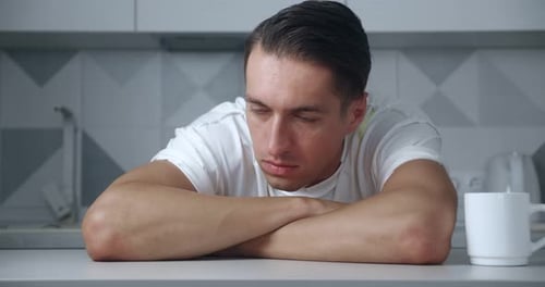 Tired Man Resting in Kitchen with Arms Crossed