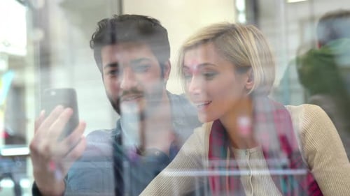 Video call. Happy couple using phone in cafe indoors