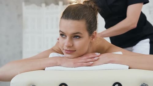 Hübsche junge Frau bei Rückenmassage im Spa-Salon