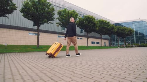 Male Businessman Goes on a Business Trip. A Man Goes To the Airport Holding Luggage in His Hand.