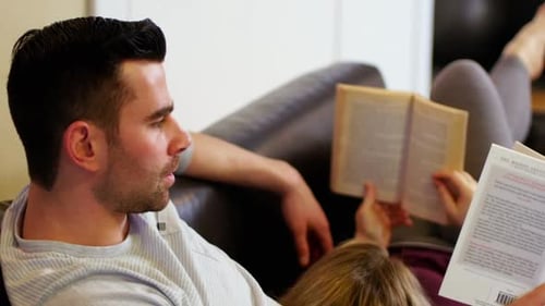 Couple lying on sofa and reading books