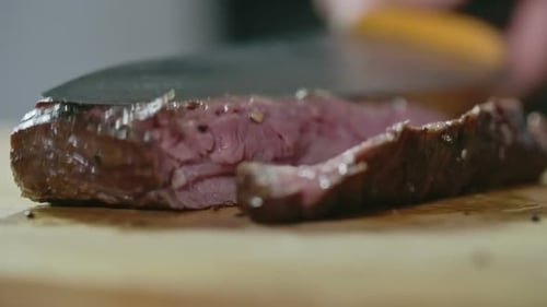 Slicing cooked steak on wooden cutting board