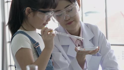 Child Conducts Science Experiment With Mentor in Laboratory
