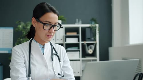 Woman Doctor Typing on Laptop in Medical Office