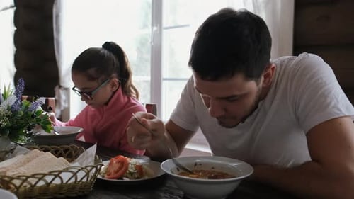 Young Man and Little Girl Eating Soup in a Restaurant