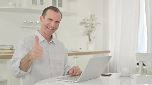 Cheerful Man Giving Thumbs Up at Laptop
