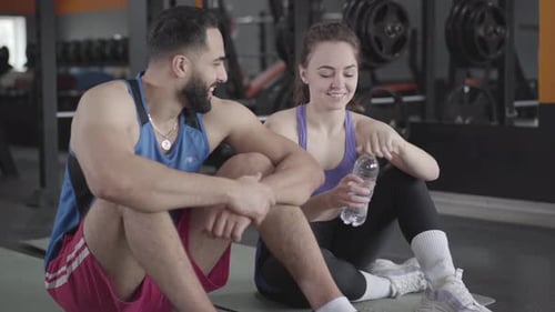 Young Middle Eastern Man Flirting with Slim Caucasian Woman in Gym